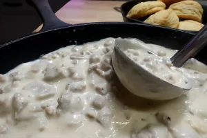 sausage-gravy-over-biscuits-in-cast-iron-skillet-with-ladle