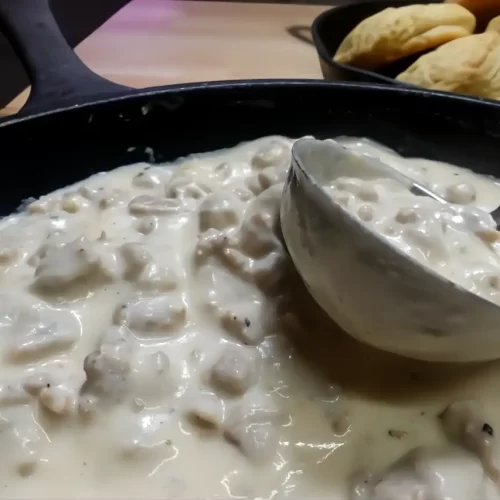 sausage-gravy-over-biscuits-in-cast-iron-skillet-with-ladle