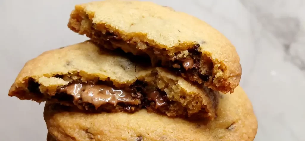 stack of reese's stuffed chocolate chip cookies one broke in 1/2 showing peanut butter oozing out