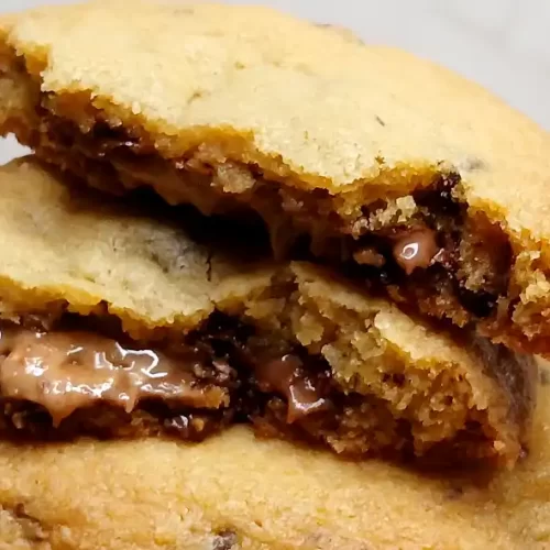 stack of reese's stuffed chocolate chip cookies one broke in 1/2 showing peanut butter oozing out