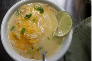 top-view-creamy-white-chicken-chili-with-lime-and-cheese-garnish.