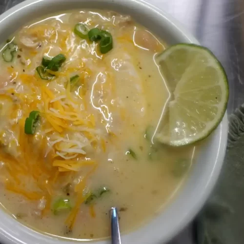 top-view-creamy-white-chicken-chili-with-lime-and-cheese-garnish.