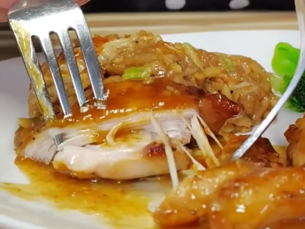 orange butter chicken close up meat being pulled apart