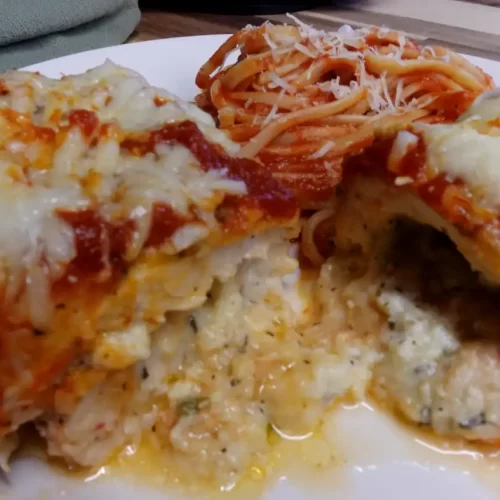 stuffed-chicken-parmesan-on-white-serving-platter-cut-in-half-showing-cheesy-center
