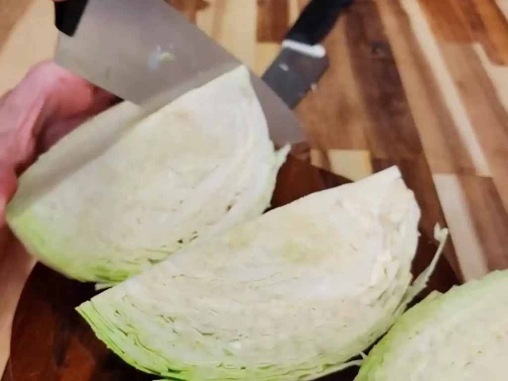 cabbage-on-cutting-board-being-cut-into-wedges