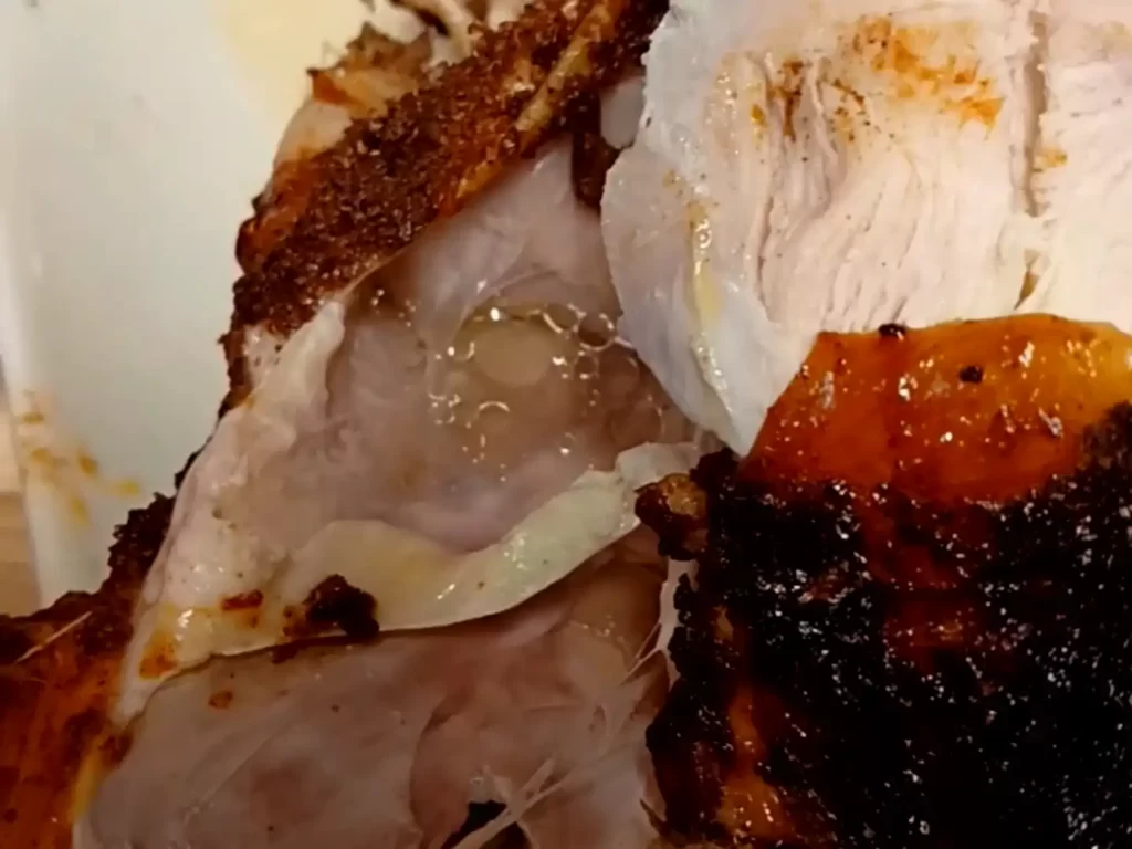 close-up-of-let-being-pulled-off-grilled-sweet-onion-ginger-beer-chicken-with-juices-showing.