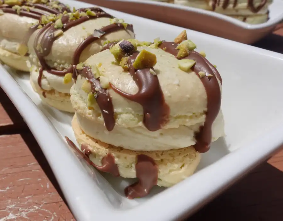 close-up-pistachio-cream-macaron-with-chocolate-drizzle-and-pistachio-crumbs