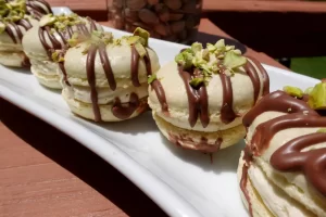 pistachio-cream-macarons-on-white-tray-drizzled-with-chocolate-and-salted-pistachios.