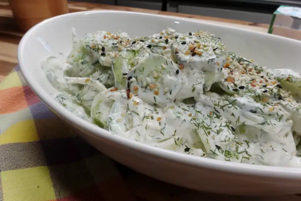 side-view-creamy-cucumber-onion-salad-topped-with-fresh-dill-and-everything-bagel-seasoning.