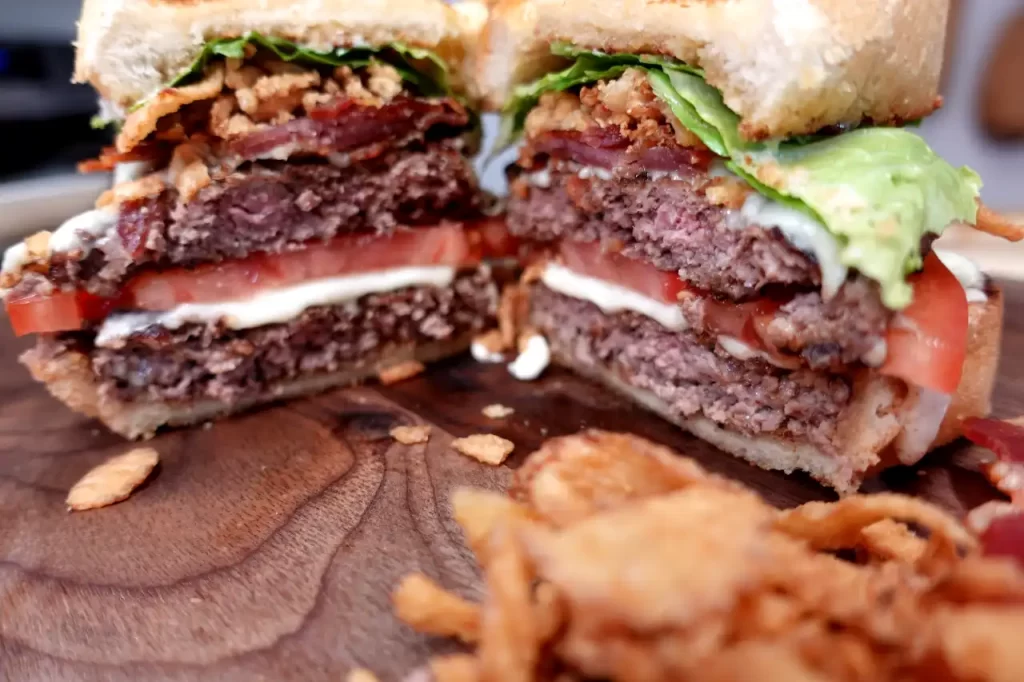 texas-toast-smash-burger-close-up-on-cutting-board-with-crispy-fried-onions.webp