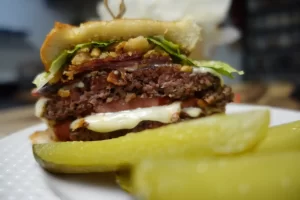 texas-toast-smash-burger-on-white-plate-with-pickles.webp