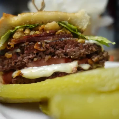 texas-toast-smash-burger-on-white-plate-with-pickles.webp