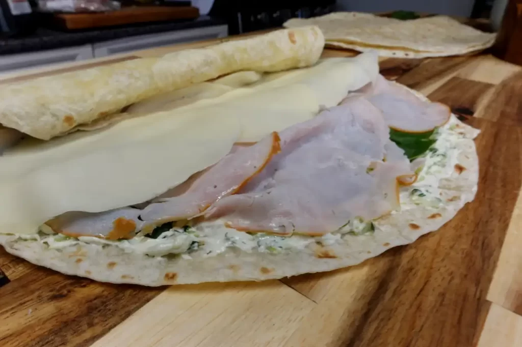 turkey cucumber dill pinwheels being rolled up