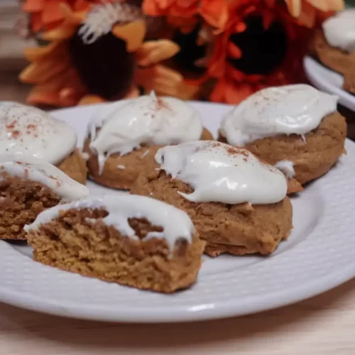 Pumpkin-cookies-with-cream-cheese-frosting-arranged-on-a-plate.