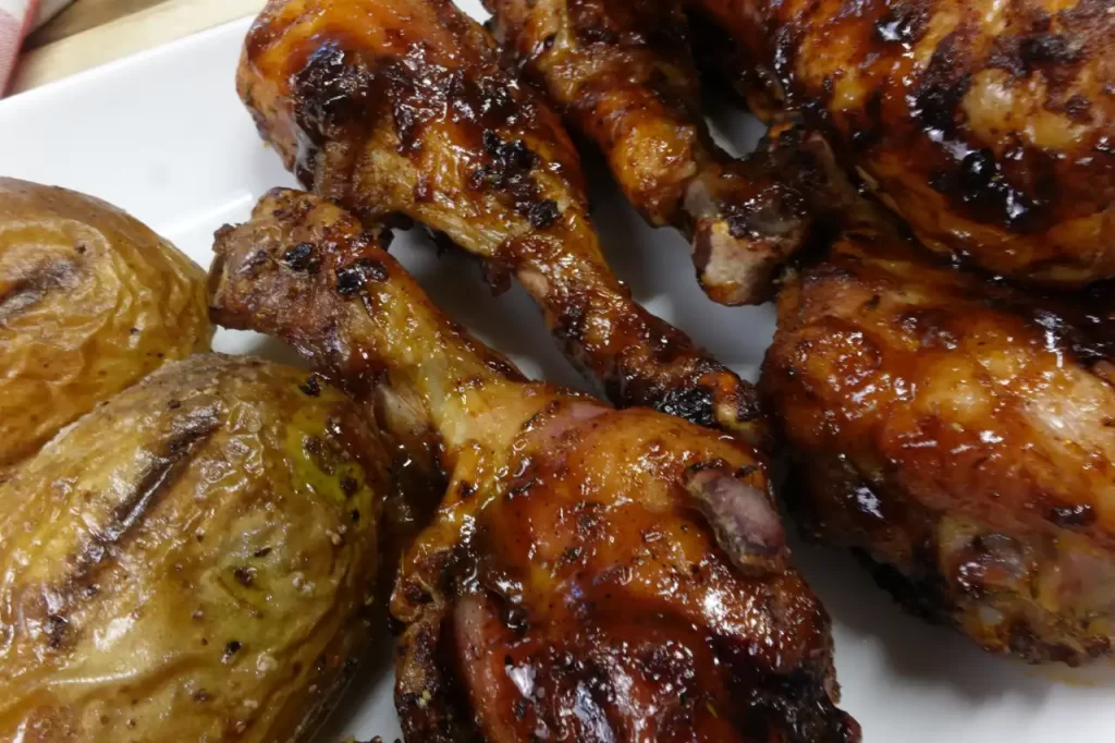 Juicy-smoked-chicken-drumsticks-with-caramelized-BBQ-sauce-arranged-on-a-platter-alongside-seasoned-roasted-potatoes