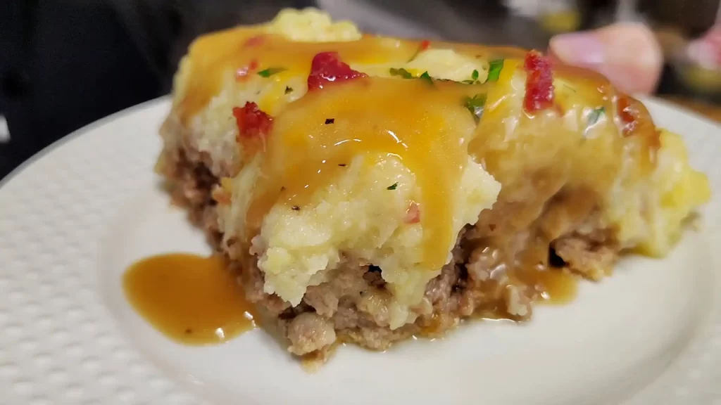 Serving-of-loaded-meatloaf-casserole-with-bacon-cheddar-mashed-potatoes-and-beef-gravy.