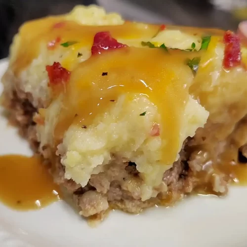 Serving-of-loaded-meatloaf-casserole-with-bacon-cheddar-mashed-potatoes-and-beef-gravy.